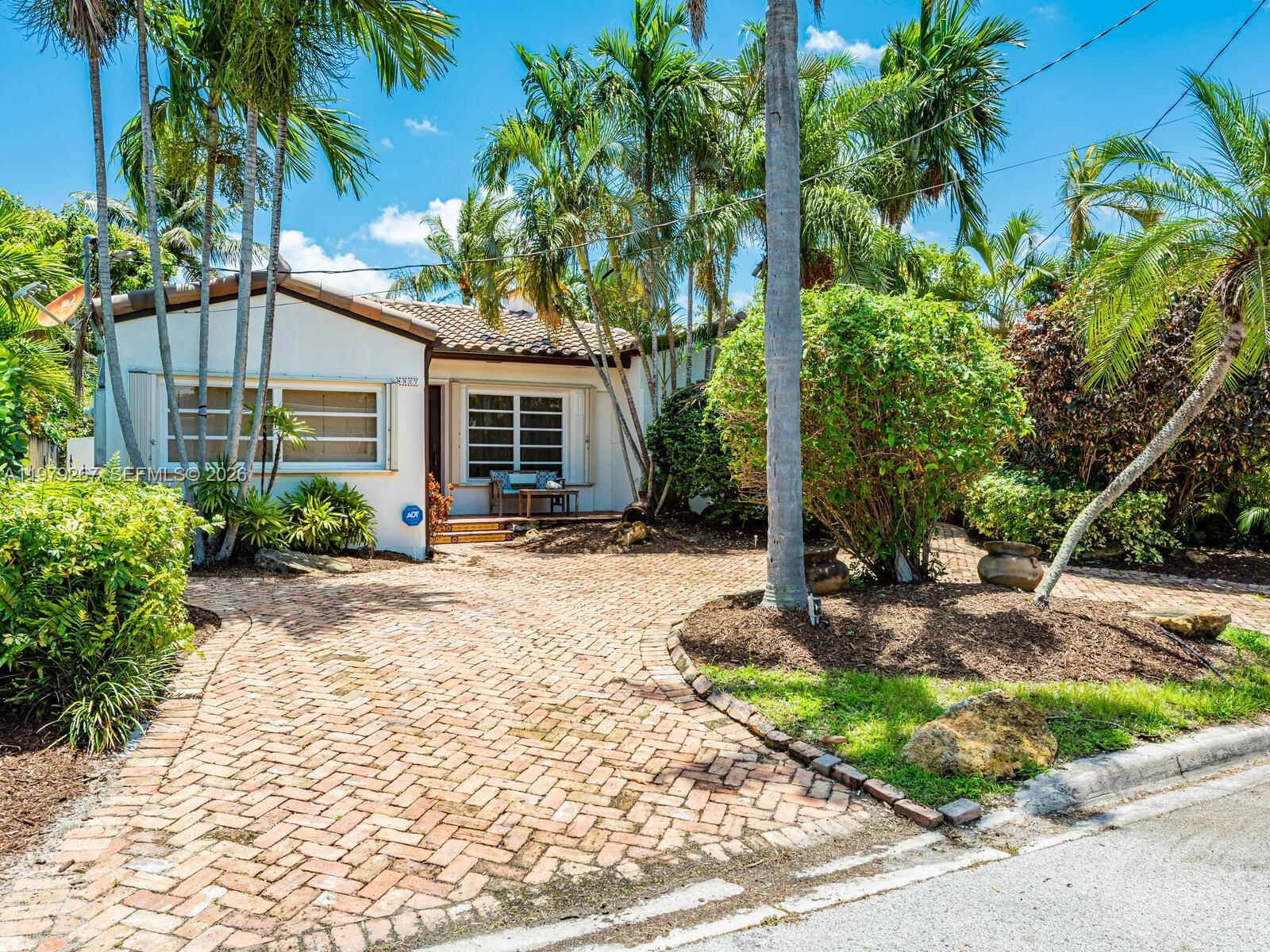 8927 Hawthorne Avenue Surfside, FL 33154 - Photo 3 of 40 a front view of a house with garden and trees