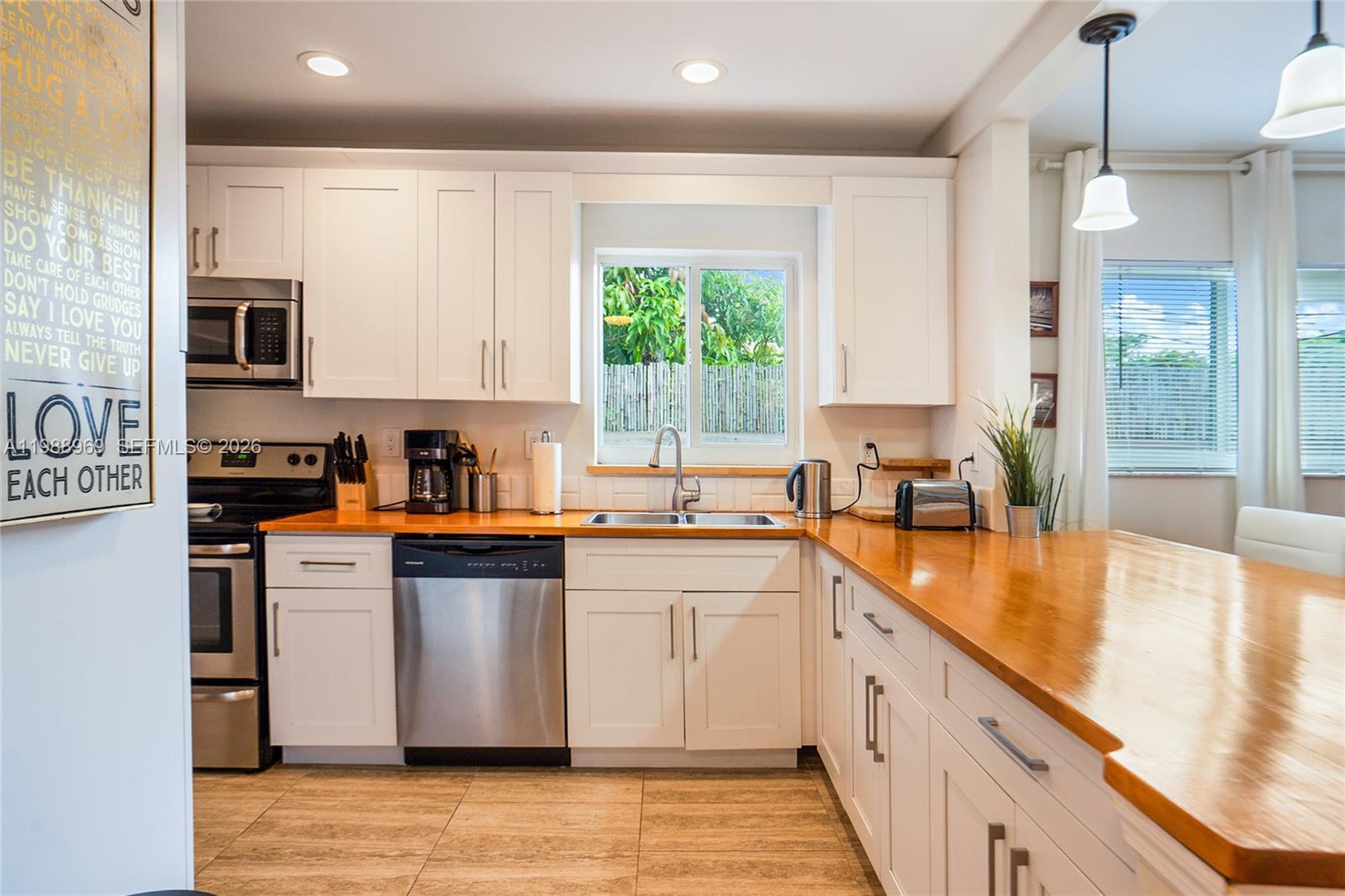 113 Southwest 2nd Street Hallandale Beach, FL 33009 - Photo 9 of 50 a kitchen with stainless steel appliances granite countertop a stove a sink and white cabinets with wooden floor