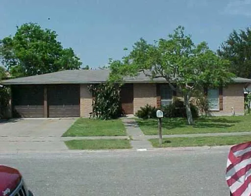 a front view of a house with a garden and trees