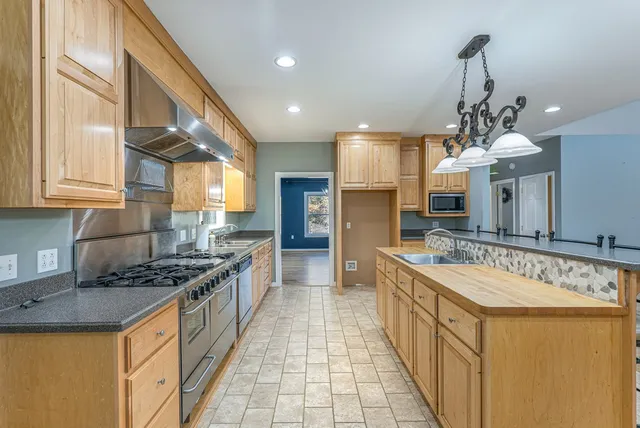 a kitchen with stainless steel appliances granite countertop a sink stove and cabinets