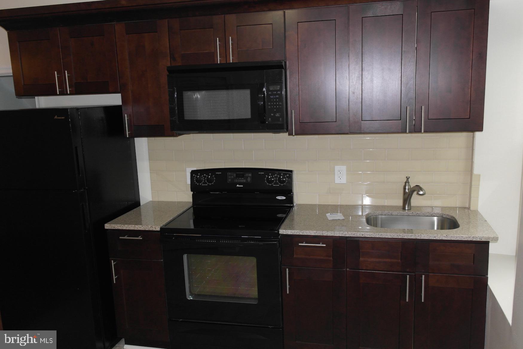 a kitchen with granite countertop stainless steel appliances a stove microwave and sink