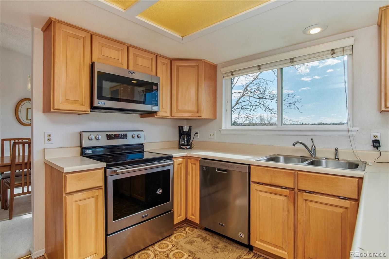 462 Northridge Road Highlands Ranch, CO 80126 - Photo 9 of 36 a kitchen with stainless steel appliances granite countertop a sink a stove a microwave and wooden cabinets