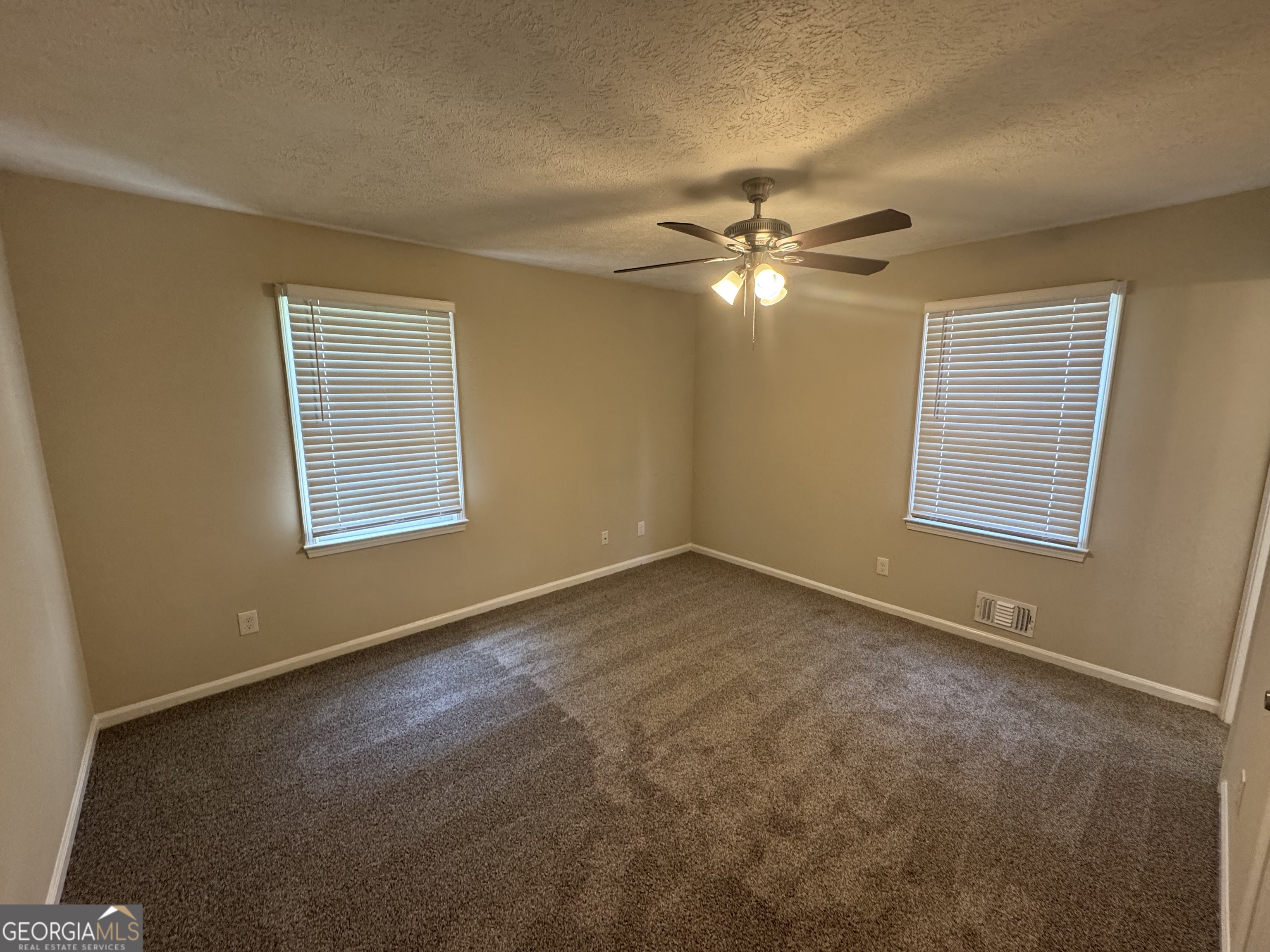 8347 Union Grove Road Lithonia, GA 30058 - Photo 8 of 9 an empty room with windows and fan
