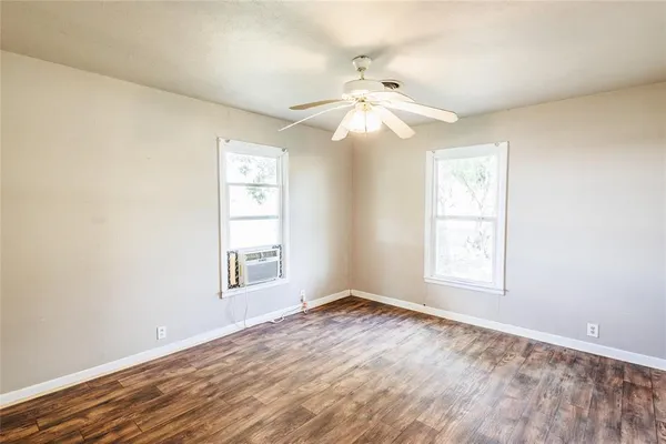 an empty room with windows and fan