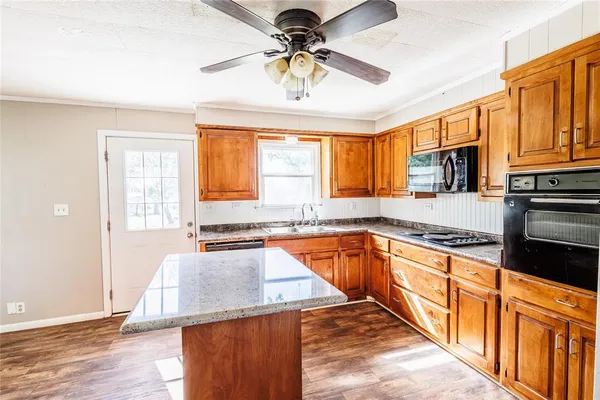 a kitchen with stainless steel appliances granite countertop a stove top oven a sink dishwasher a dining table and chairs with wooden floor