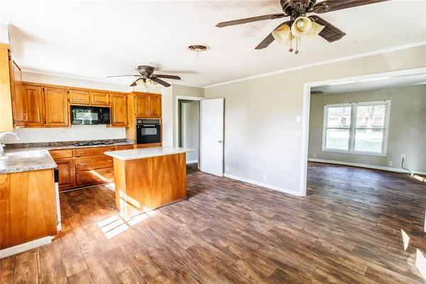 an empty room with wooden floor ceiling fan and windows