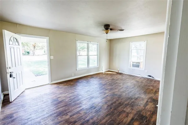 an empty room with wooden floor and windows