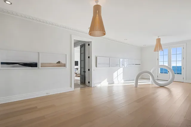 a room with lots of white furniture and wooden floor