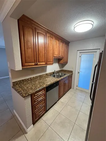 a kitchen with granite countertop a stove a sink and a refrigerator