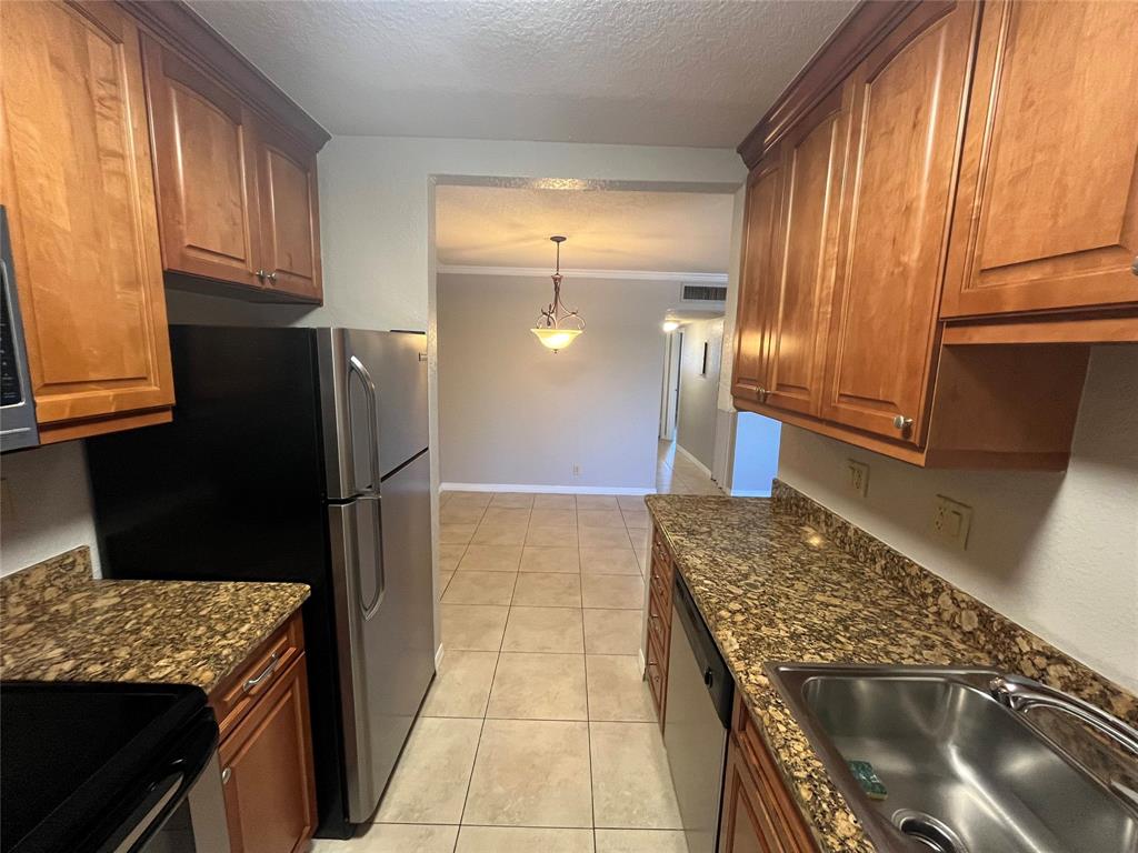 2020 Northeast 56th Street, Unit 208 Fort Lauderdale, FL 33308 - Photo 4 of 54 a kitchen with granite countertop a refrigerator a stove and wooden cabinets