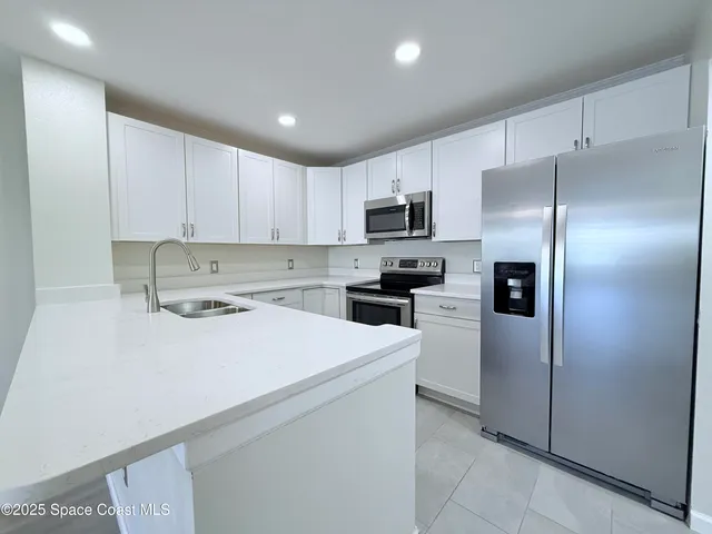 a kitchen with stainless steel appliances a refrigerator sink and white cabinets