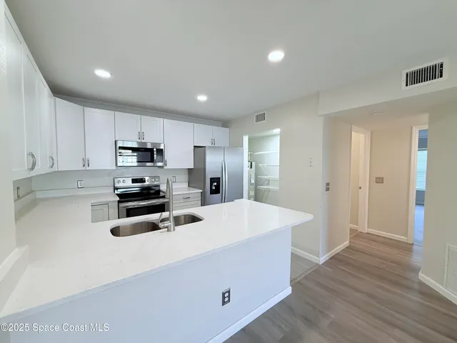 a kitchen with white cabinets appliances and sink