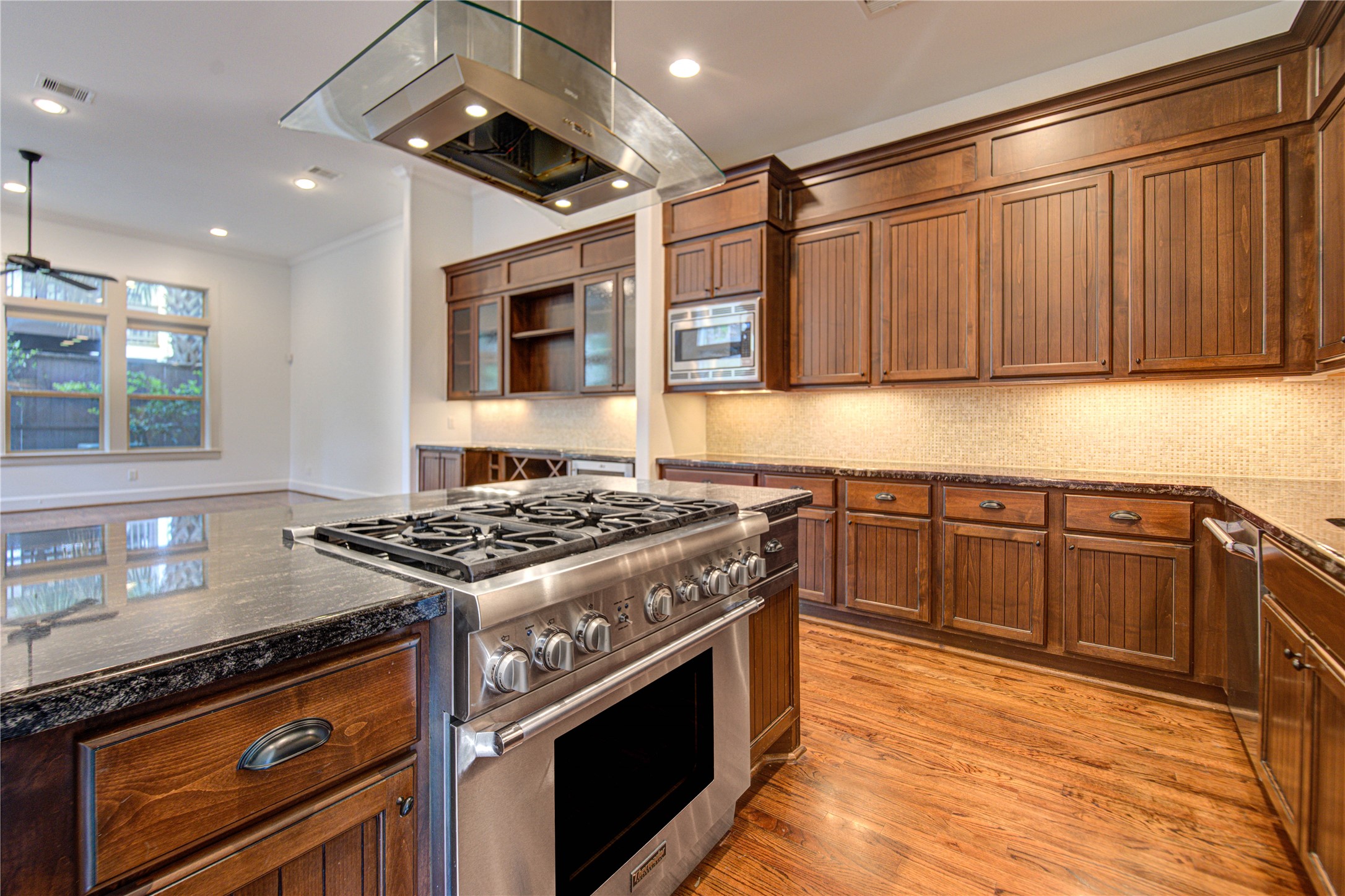6520 Rodrigo Street Houston, TX 77007 - Photo 6 of 44 Gourmet kitchen featuring a large center island, granite countertops, custom wood cabinetry, professional-grade gas range, and stainless steel vent hood.