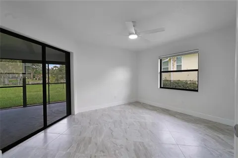 an empty room with windows and ceiling fan