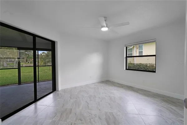 an empty room with windows and ceiling fan