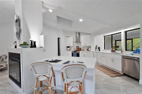 a kitchen with stainless steel appliances granite countertop a dining table chairs refrigerator and sink