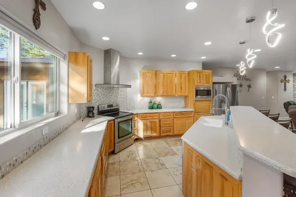 a large kitchen with kitchen island a large window a sink and stainless steel appliances