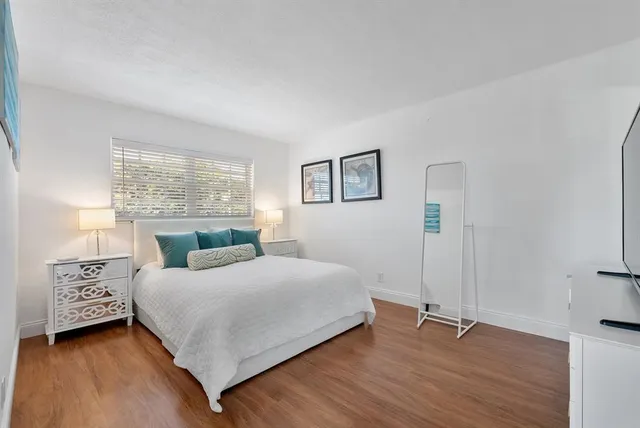 a bedroom with a bed a window and a wooden floor