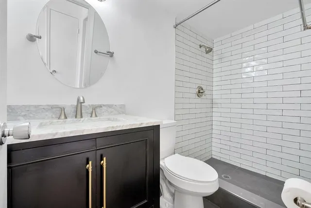 a bathroom with a granite countertop toilet sink and mirror