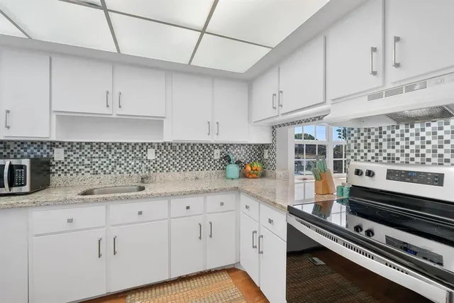 a kitchen with white cabinets and appliances