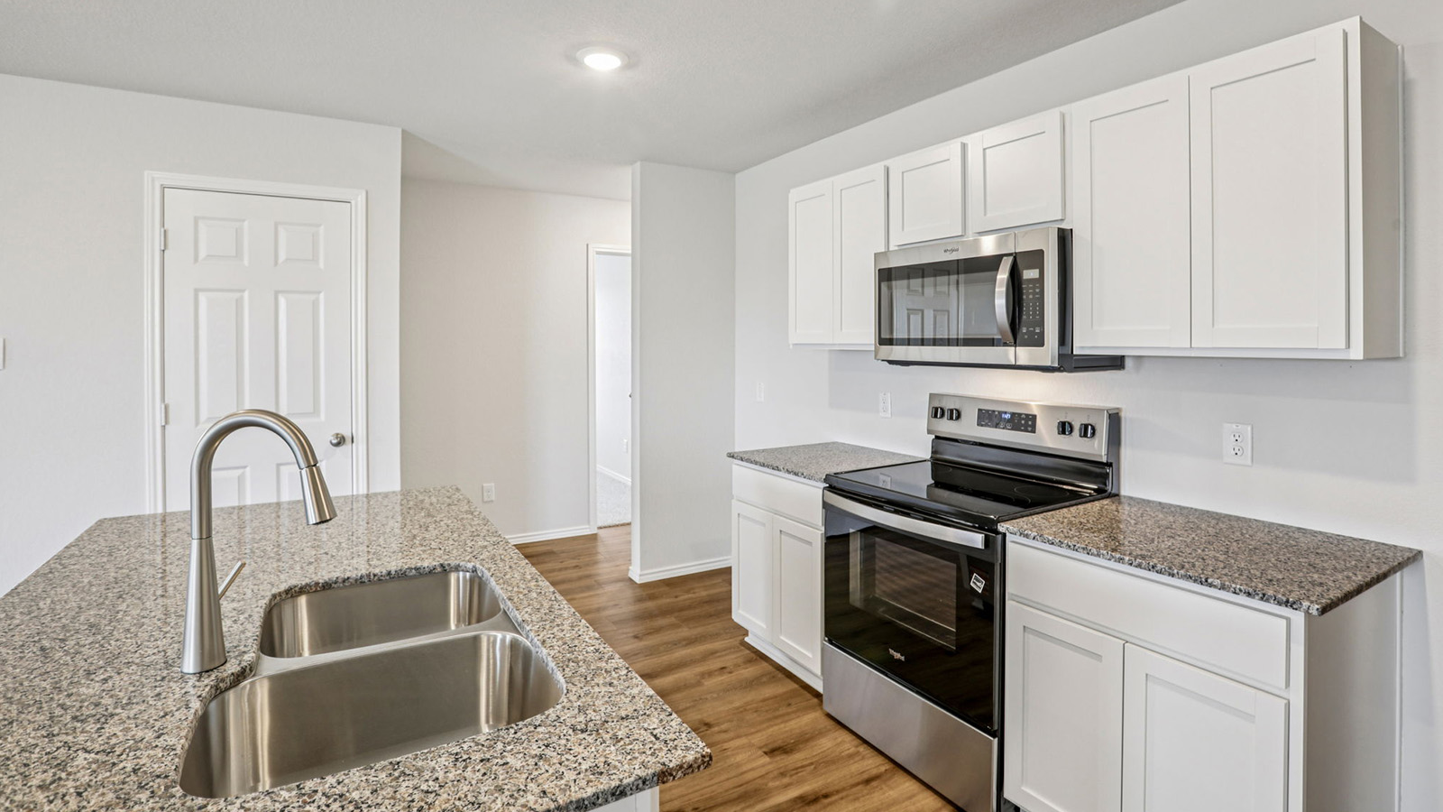 148 Wyatt Way Jarrell, TX 76537 - Photo 5 of 33 Kitchen featuring wood-finish flooring, white cabinetry, speckled countertops, stainless steel appliances, and a double basin sink with a pull-down faucet