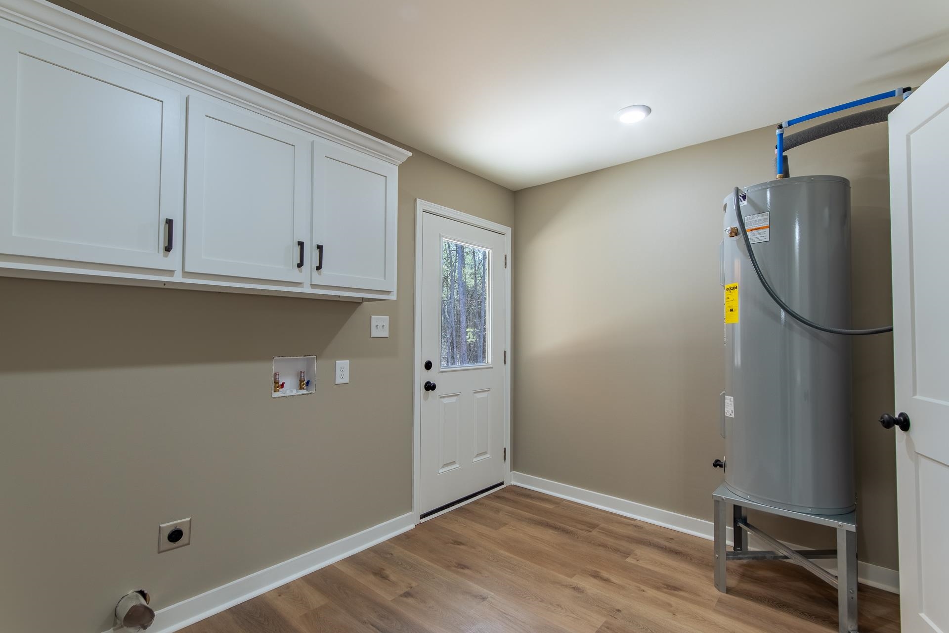 1471 Chambers Store Road Michie, TN 38357 - Photo 19 of 38 Washroom with water heater, hookup for an electric dryer, baseboards, light wood-style floors, and cabinet space