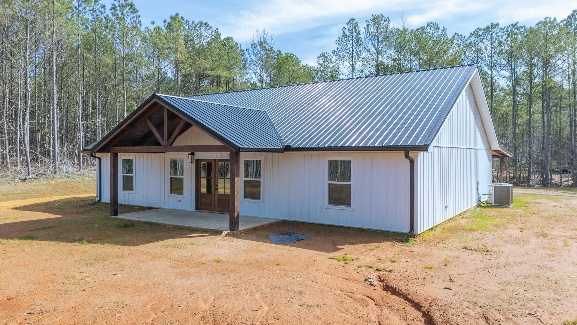 1471 Chambers Store Road Michie, TN 38357 - Photo 3 of 38 View of front of home with metal roof, a patio, a forest view, cooling unit, and french doors