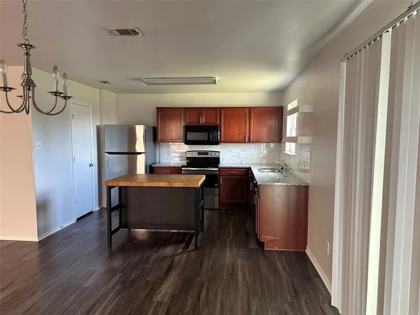 an empty room with wooden floor chandelier fan and windows