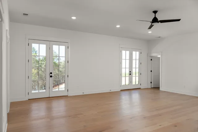 an empty room with wooden floor and ceiling fan