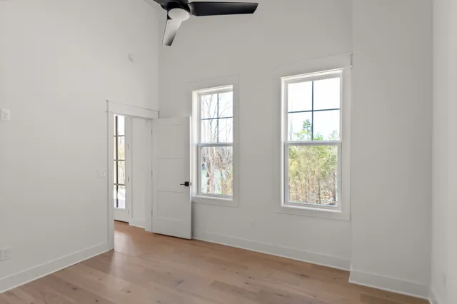 an empty room with a ceiling fan and wooden floor