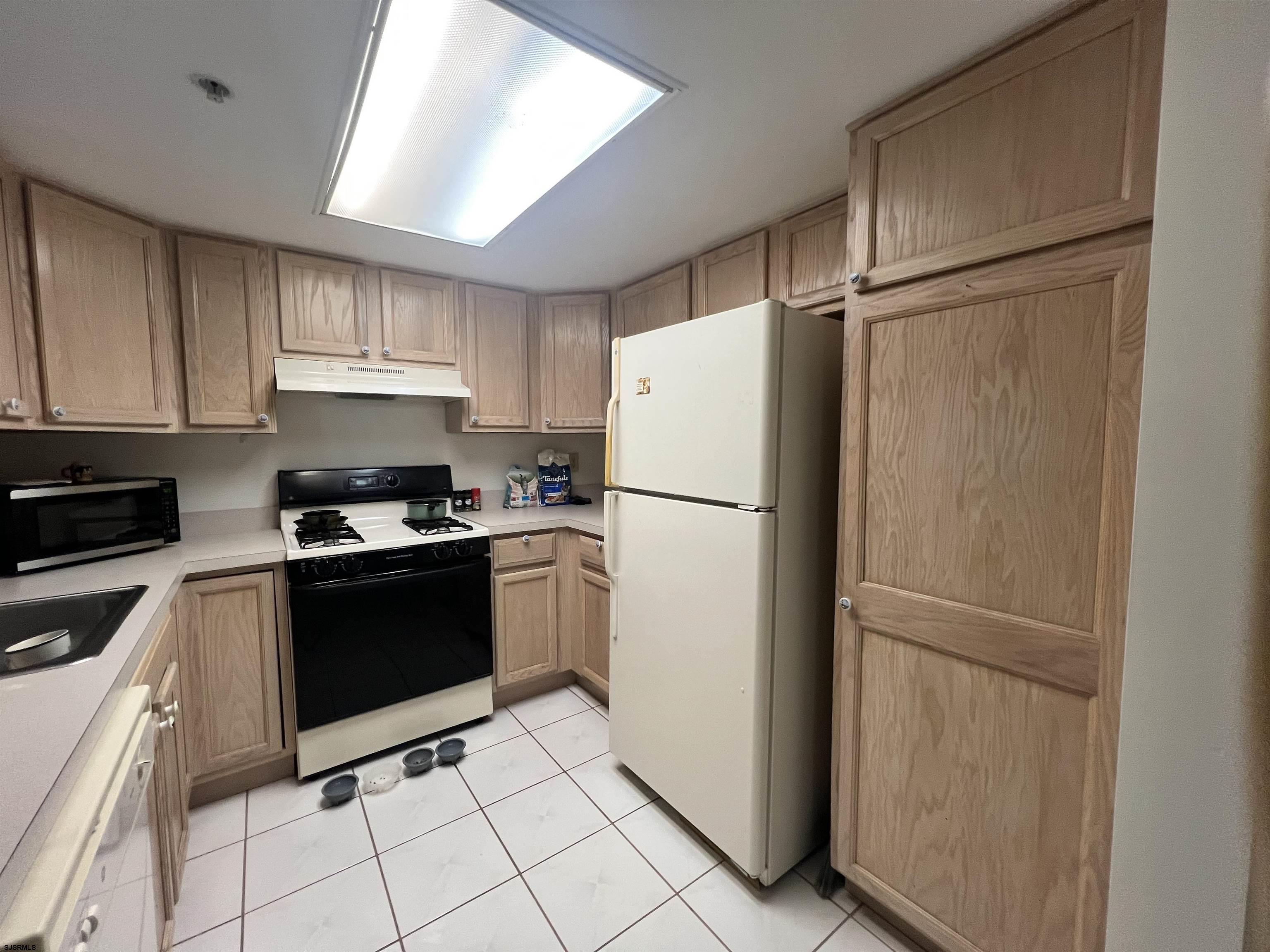 4310 Dolphin Avenue, Unit 4310 Northfield, NJ 08225 - Photo 10 of 21 a kitchen with a refrigerator a stove top oven and cabinets