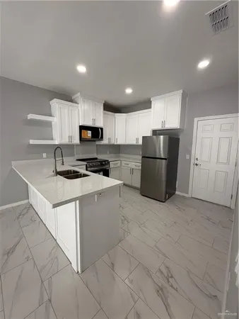 a kitchen with granite countertop a refrigerator and a stove top oven