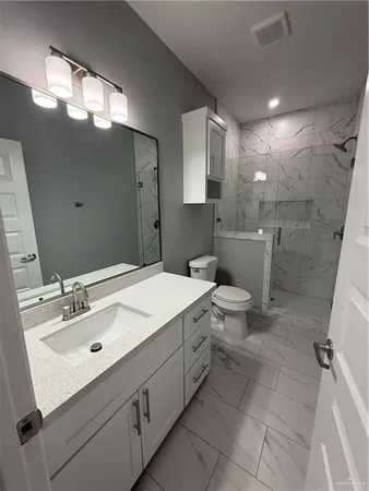 a bathroom with a sink vanity mirror and toilet