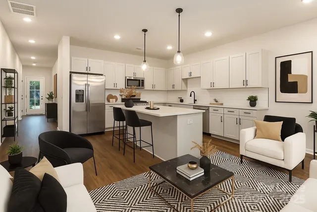 a living room with stainless steel appliances furniture a rug kitchen view and a chandelier