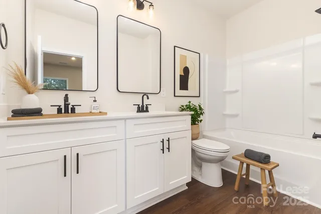 a bathroom with a toilet a sink a tub and mirror