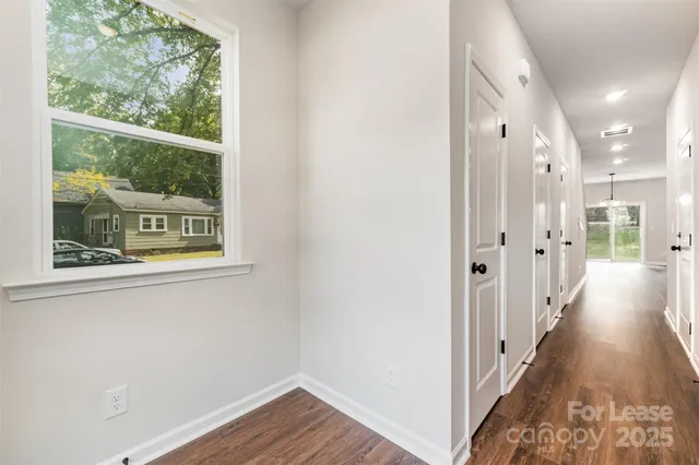a view of a hallway with wooden floor and a window