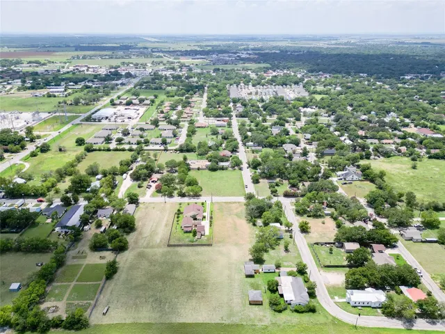 an aerial view of residential houses with outdoor space and trees