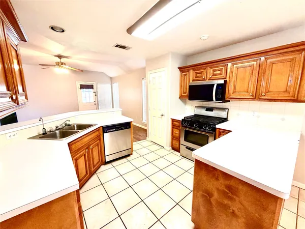 a kitchen with stainless steel appliances a stove top oven a sink a counter top space and cabinets