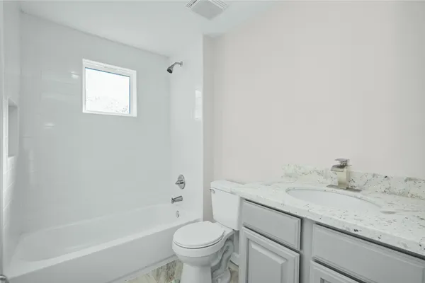 a bathroom with a granite countertop sink a toilet and bathtub