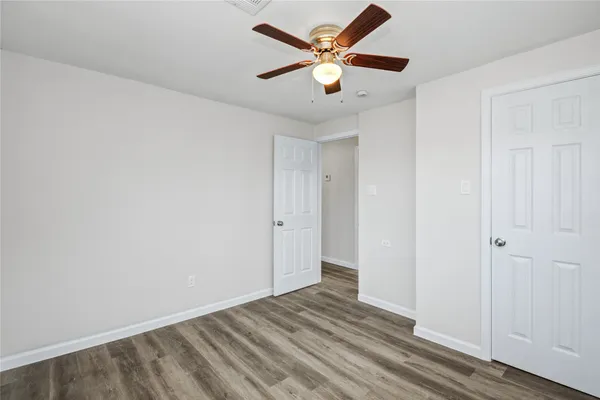 an empty room with wooden floor and a ceiling fan