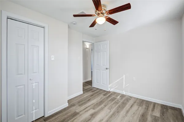 an empty room with wooden floor fan and windows