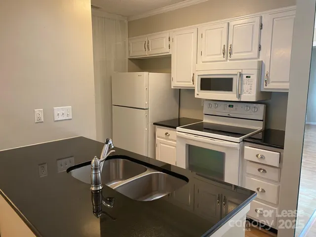 a kitchen with granite countertop a sink stove and refrigerator
