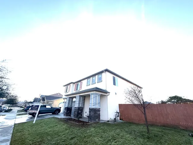 a view of a house with a yard plants and large tree