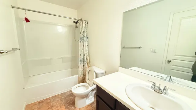 a bathroom with a sink a toilet a mirror a bathtub and shower