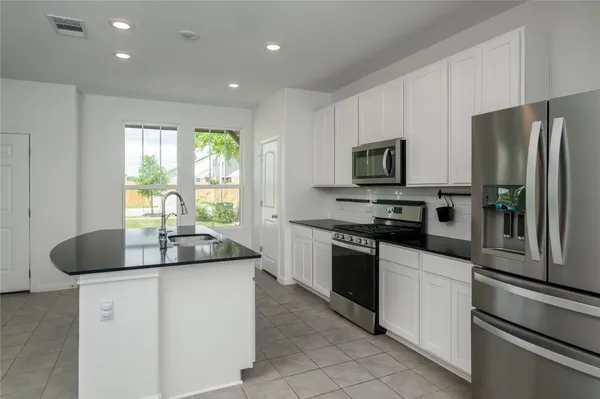 a kitchen with stainless steel appliances granite countertop a sink a stove and a refrigerator