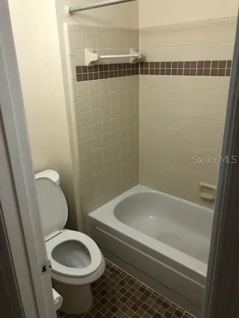 a bathroom with a granite countertop toilet and a bathtub