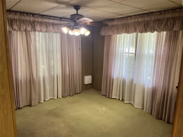 a view of an empty room with a window and a chandelier fan