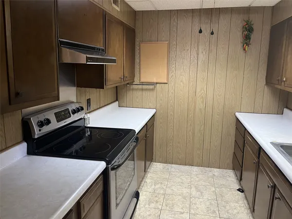 a kitchen with a sink dishwasher a stove and a refrigerator with wooden cabinet