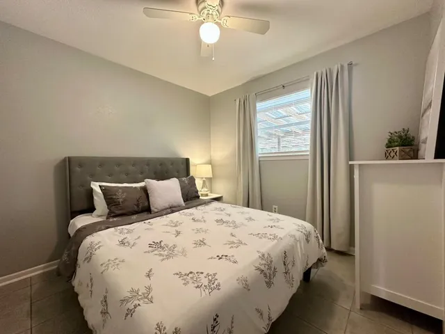 a large bed sitting in a bedroom next to a window and a chandelier