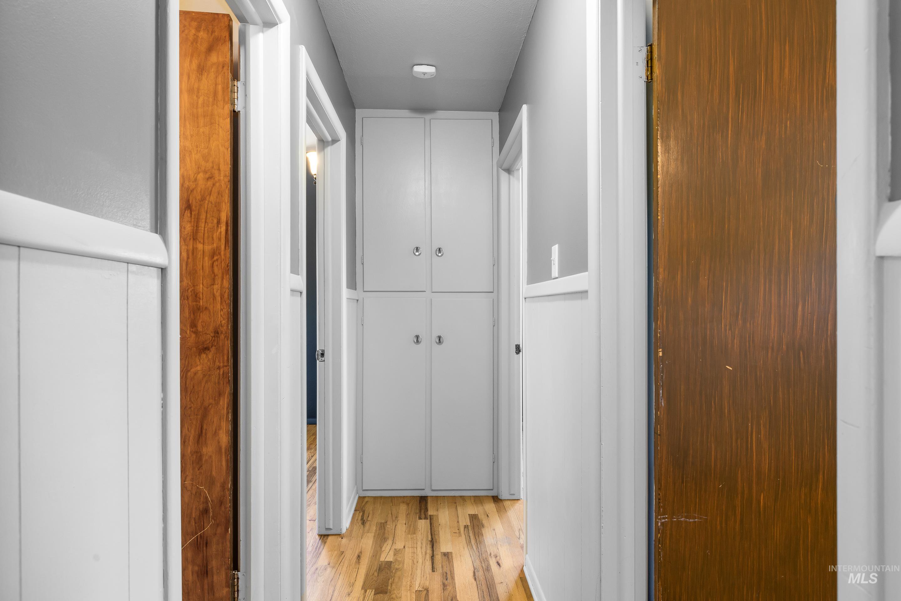 708 South Phillippi Street Boise, ID 83705 - Photo 12 of 25 Hallway featuring wood-finish flooring, white paneled wainscoting, and built-in white cabinetry with ring hardware